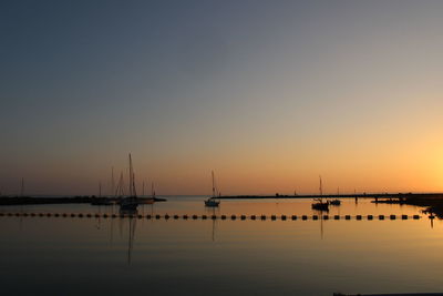 Silhouette sailboats in sea against clear sky during sunset