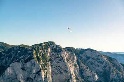 Paragliding pilot flying above mountains in fall colors, altaussee, austria.