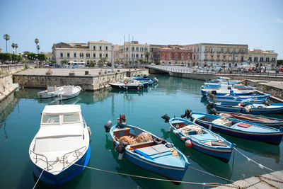 Boats moored at harbor against buildings in city