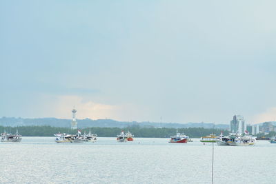 Sailboats moored in sea against sky