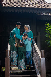 Full length of a man holding woman standing against built structure