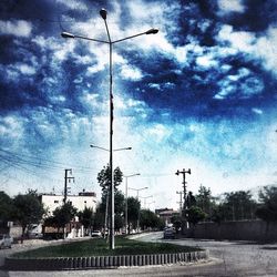 Electricity pylon against cloudy sky