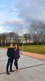 Full length portrait of friends standing by tree against sky