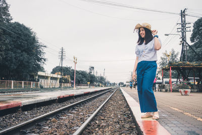 Woman standing on railroad track against sky