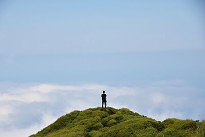 Rear view of man standing on mountain against sky