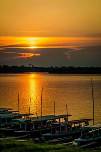 Boats moored in sea at sunset