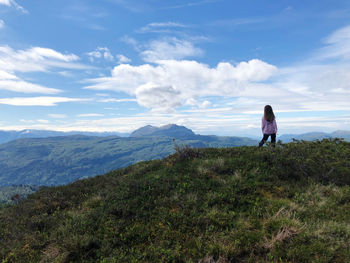 Rear view of woman looking at mountains against sky