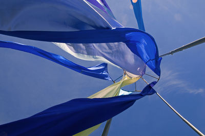 Low angle view of fabric waving against blue sky
