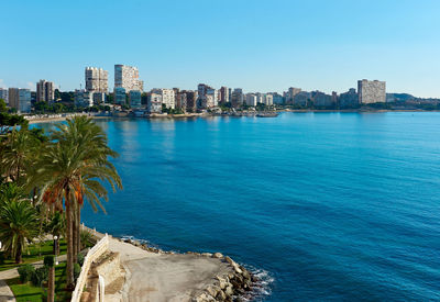 Sea by city against clear blue sky