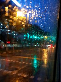 Defocused image of illuminated city seen through wet window