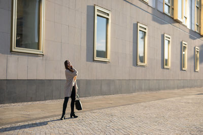 Portrait of woman standing on street against building in city