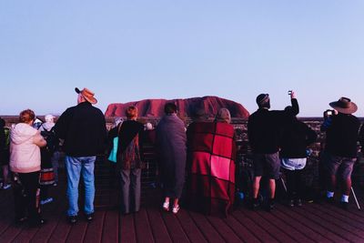 Rear view of people standing against clear sky