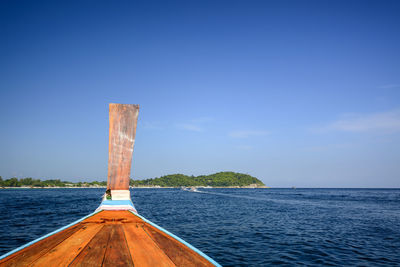 Close-up of boat sailing on sea against clear blue sky