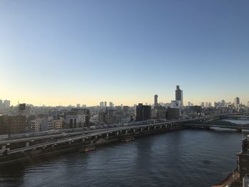 Bridge over river in city against clear sky