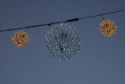 Low angle view of illuminated fairy lights decoration hanging against clear blue sky