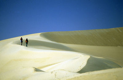 Low angle view of sand dunes at desert against blue sky