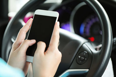 Midsection of man using mobile phone in car