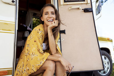 Portrait of smiling woman sitting by motor home