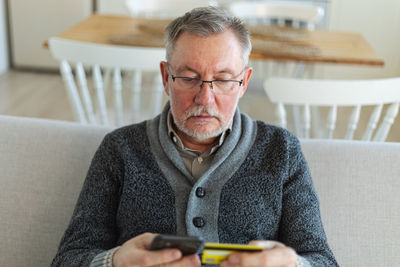 Young man using mobile phone while sitting on sofa at home