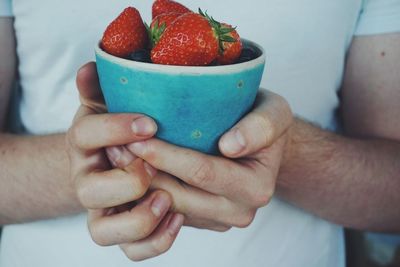 Midsection of man holding strawberries in bowl