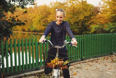 Smiling young woman standing by railing in park