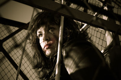 Low angle view of young woman with messy hair looking away by railing