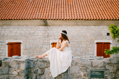 Side view of bride siting against house