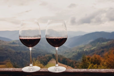 Two glasses of red wine standing with a beautiful scenic mountain view. 