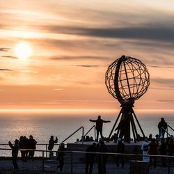 Silhouette people on beach against sky during sunset