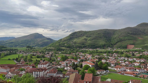 Aerial view of townscape by mountain against sky