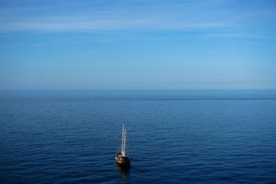 Sailboat sailing in sea against blue sky