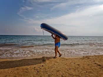 Man carrying raft on beach
