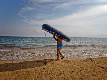 Full length of boy on beach against sky