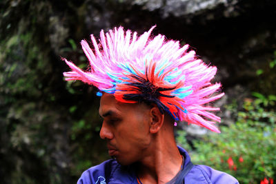 Man wearing wig while standing against trees