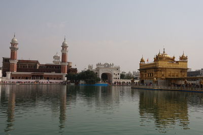 View of buildings by river against sky