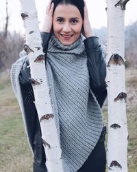 Portrait of smiling woman standing by tree trunks