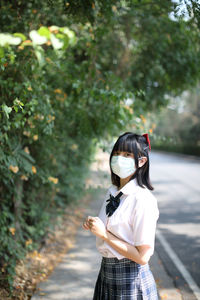 Portrait of young woman wearing mask standing outdoors