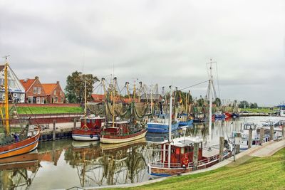 Boats moored at harbor against sky