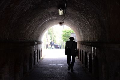 Rear view of man walking in tunnel