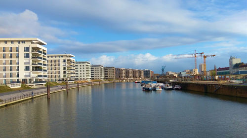 Buildings by river against sky in city