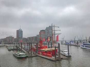 Sailboats moored at harbor against sky