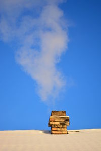 Low angle view of smoke stack on snow covered roof