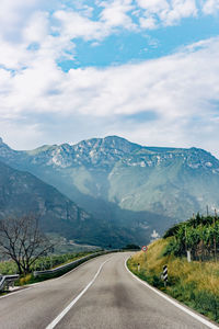 Road leading towards mountains against sky