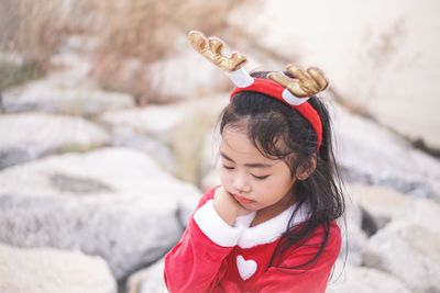 High angle view of sad girl wearing red dress and headband while standing on rocks