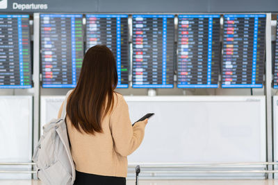 Rear view of woman checking for flight schedule at portrait