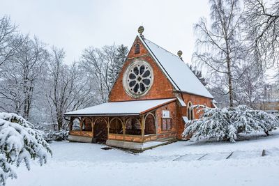 Built structure by snow covered building against sky