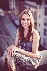 Portrait of a smiling young woman sitting on a rooftop