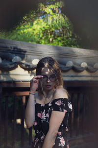 Beautiful young woman standing by wall outdoors