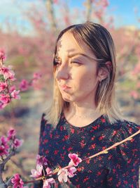 Portrait of woman with pink flowers against blurred background