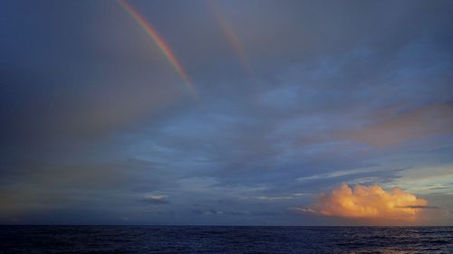 Scenic view of rainbow over sea against sky
